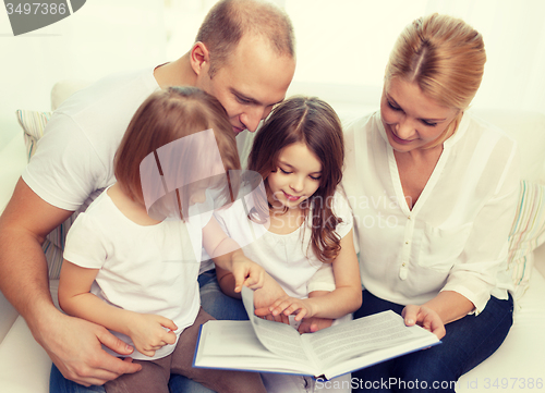 Image of smiling family and two little girls with book