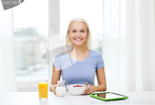 Image of smiling woman with tablet pc eating breakfast 