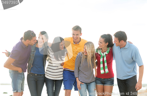 Image of group of happy friends talking on beach