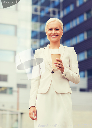 Image of smiling businesswoman with paper cup outdoors