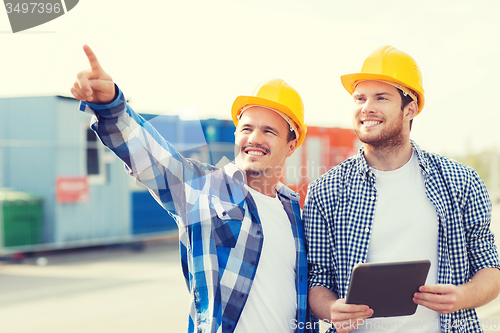 Image of smiling builders in hardhats with tablet pc