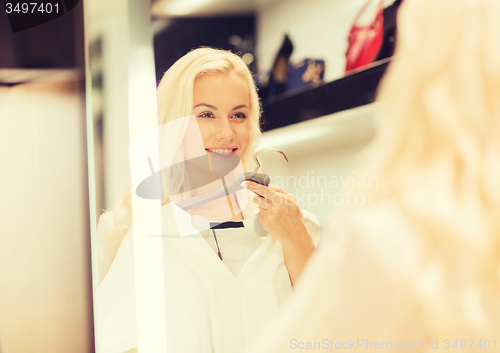 Image of happy young woman choosing clothes in mall