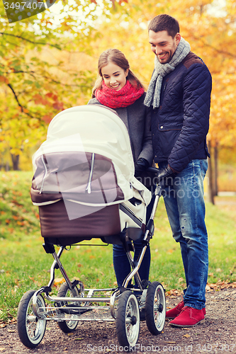 Image of smiling couple with baby pram in autumn park
