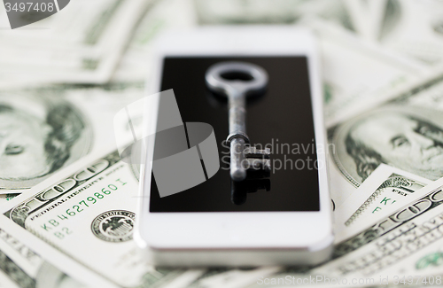 Image of close up of smartphone with key and dollar money