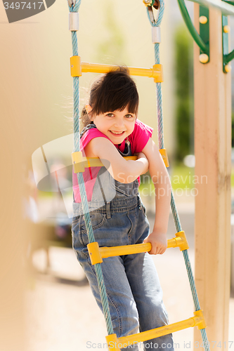 Image of happy little girl climbing on children playground
