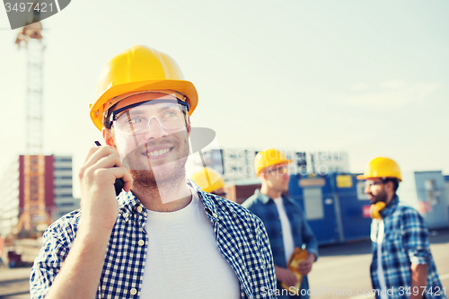 Image of group of smiling builders in hardhats with radio