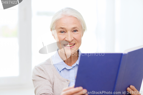 Image of happy smiling senior woman reading book at home