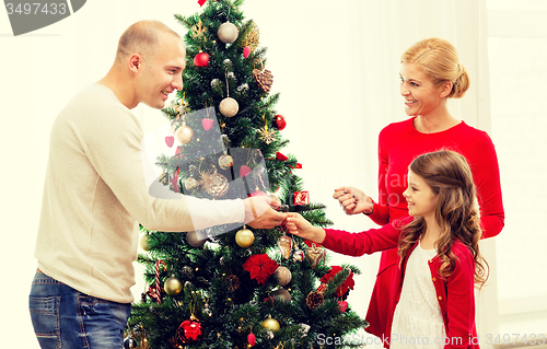 Image of smiling family decorating christmas tree at home