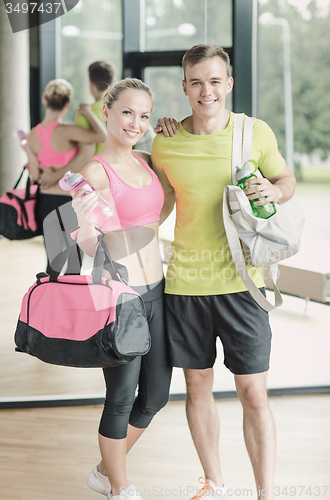 Image of smiling couple with water bottles in gym