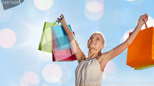 Image of smiling woman with shopping bag rising hands