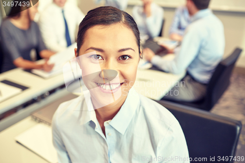 Image of group of smiling businesspeople meeting in office