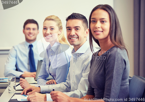 Image of group of smiling businesspeople meeting in office