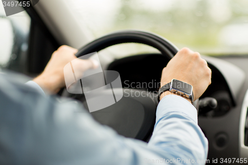 Image of close up of man with wristwatch driving car