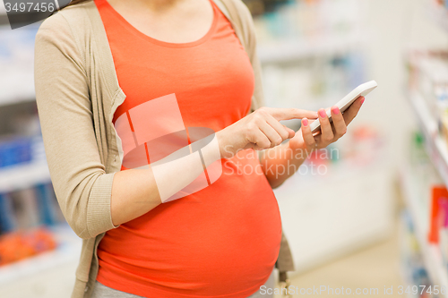 Image of pregnant woman with smartphone at pharmacy