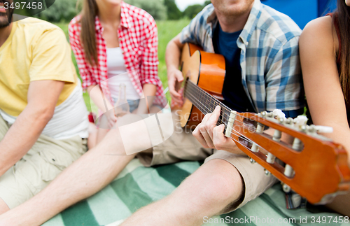 Image of happy friends with drinks and guitar at camping