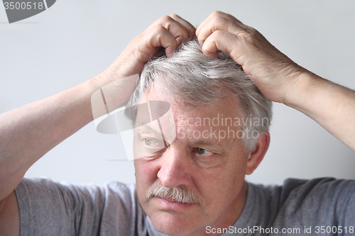 Image of Senior scratches his head.