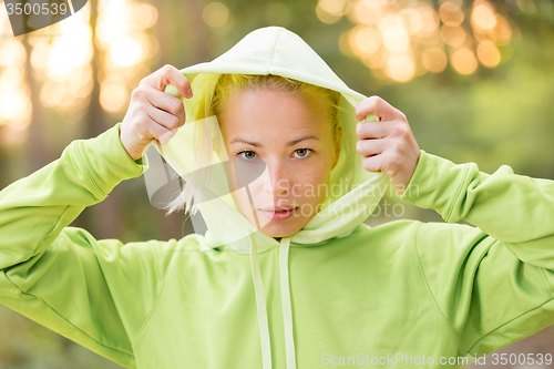 Image of Confident sporty woman wearing fashionable green hoodie. 