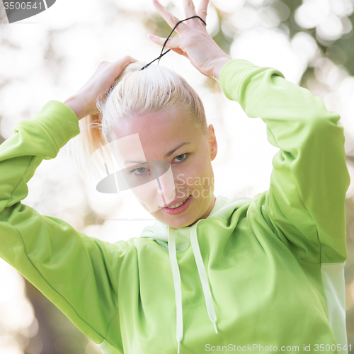 Image of Confident sporty woman wearing fashionable green hoodie. 