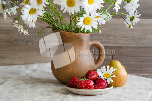 Image of Bouquet of daisies in a clay jug and strawberries with pears. Co
