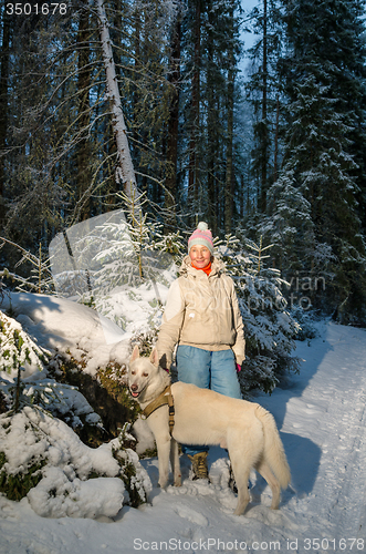 Image of Woman with dog in winter forest on a walk