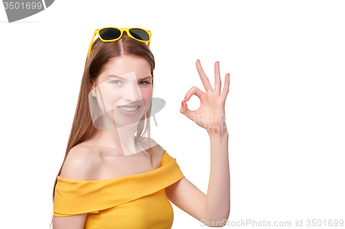 Image of Redheaded female in yellow gesturing OK