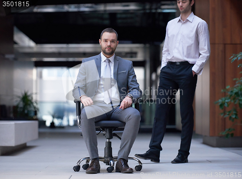 Image of business man sitting in office chair, people group  passing by