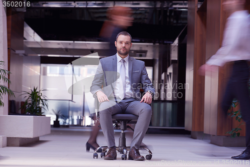 Image of business man sitting in office chair, people group  passing by