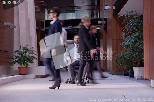 Image of business man sitting in office chair, people group  passing by