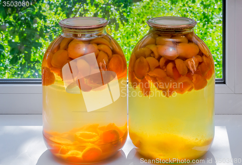 Image of Home canning: large glass cylinders with apricot compote.