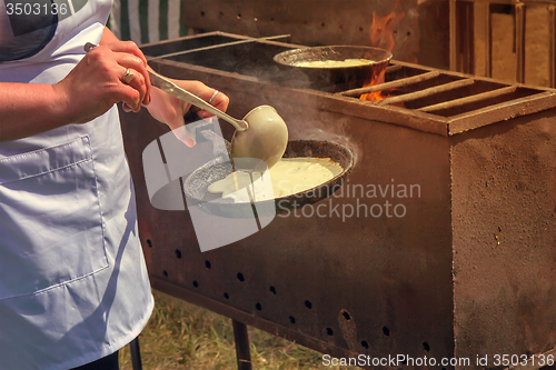 Image of Woman frying pan pancakes on the grill.