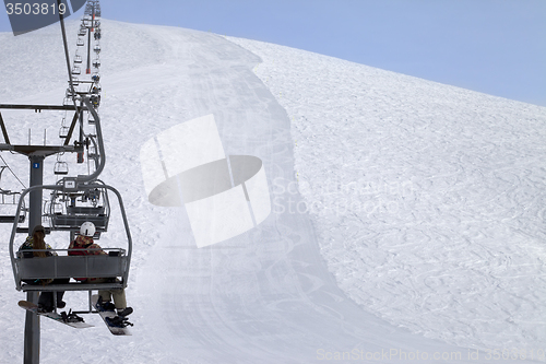 Image of Snowboarders on chair-lift and ski slope