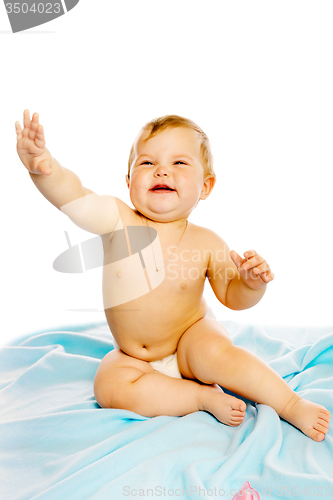 Image of baby in diaper sitting on a blue blanket. Isolated
