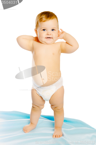 Image of baby in diaper standing on a blue blanket. Studio. Isolated