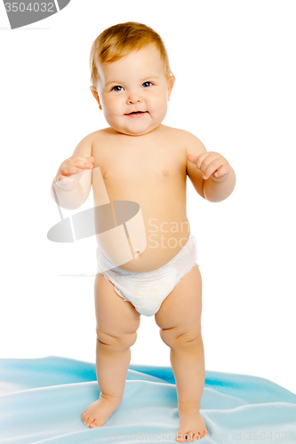 Image of baby in diaper standing on a blue blanket. Studio. Isolated