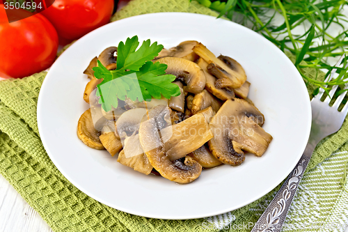 Image of Champignons fried in plate with parsley on light board