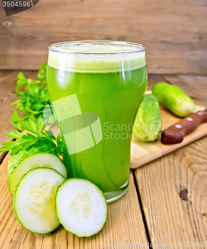 Image of Juice cucumber in tall glass on board with knife