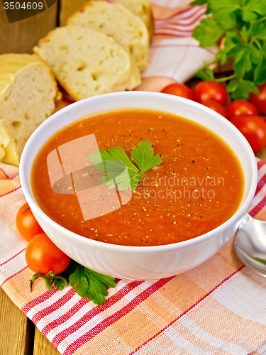 Image of Soup tomato with bread on napkin and board