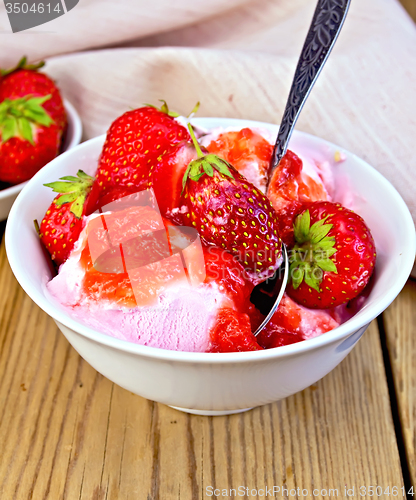 Image of Ice cream strawberry in white bowl with spoon on board