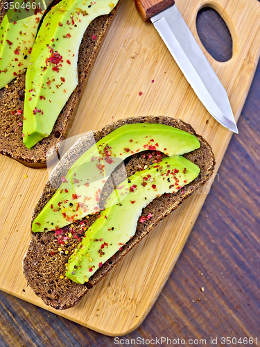 Image of Sandwich with avocado and knife on board