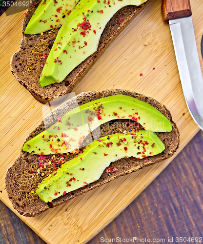 Image of Sandwich with avocado and knife on dark board