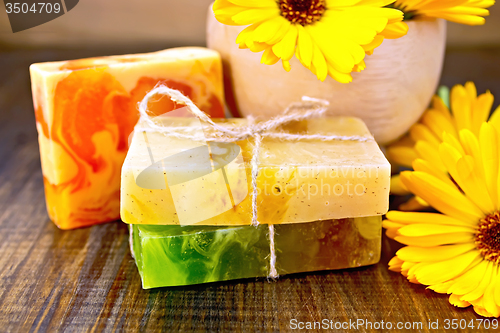 Image of Soap homemade with calendula and mortar on board