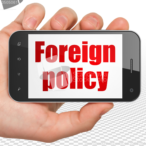 Image of Politics concept: Hand Holding Smartphone with Foreign Policy on display