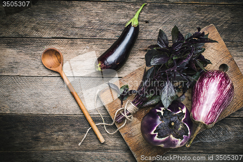 Image of Aubergines and basil on chopping board in rustic style