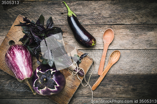 Image of Aubergines with basil and spoons on wooden table