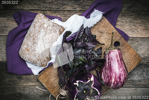 Image of Aubergines basil and bread on chopping board