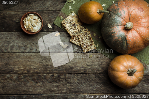 Image of Rustic style pumpkins and cookies with seeds on wooden table 