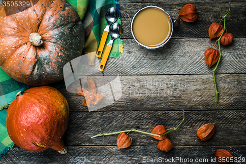 Image of Rustic style pumpkins vegetable soup and ground cherry on wood