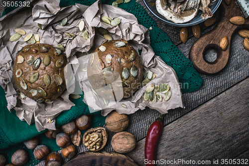 Image of buns with seeds, nuts mushrooms on wooden table 