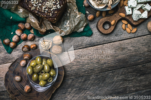 Image of nuts mushrooms bread and olives on wooden table