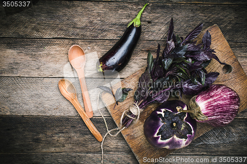 Image of Aubergines with basil and two spoon on wood boards